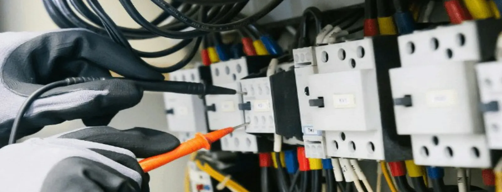 Electricista profesional revisando un tablero eléctrico con un multímetro